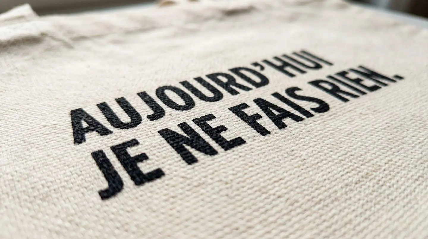 Gros plan macro sur un détail de tote bag montrant une zone de personnalisation en sérigraphie avec texture d'encre textile visible en relief